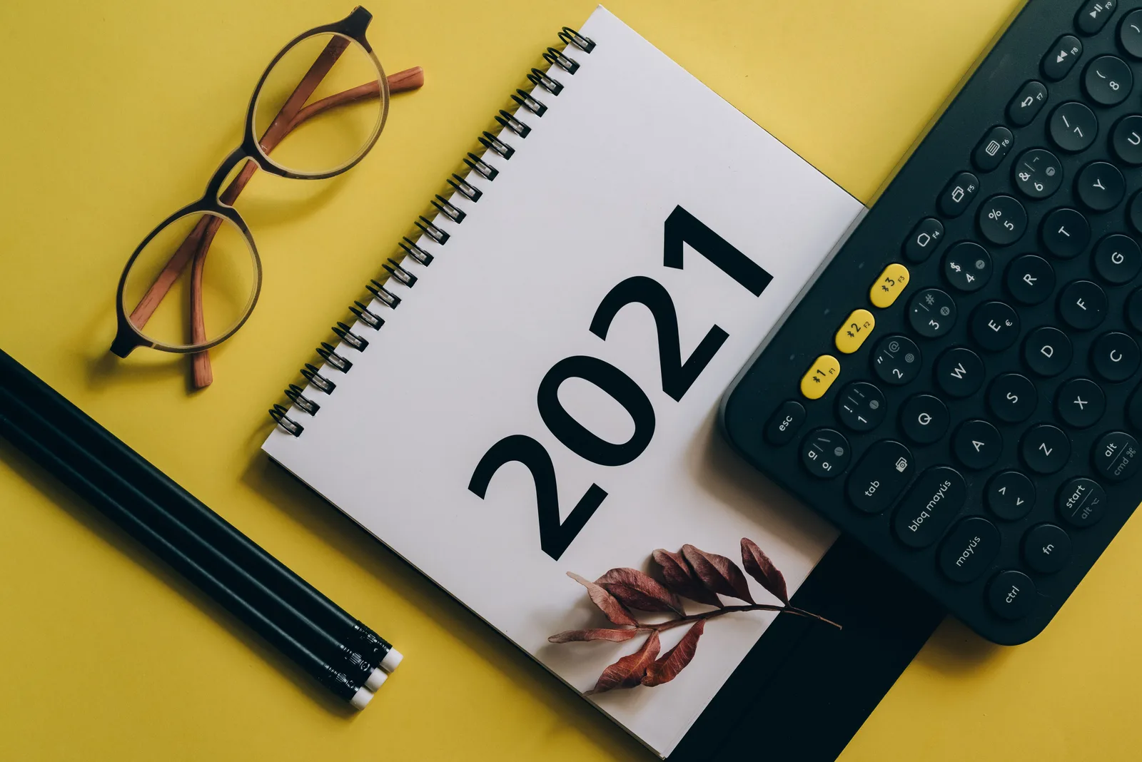 Flat lay of 2021 calendar, keyboard, and eyeglasses on yellow background. Content marketing careers: a focused business guide