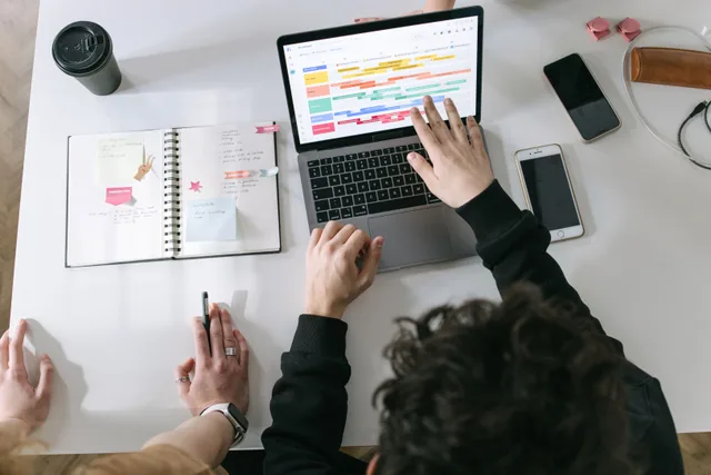 Two people collaborating on a laptop and planner at a vibrant modern office desk. How to think about digital marketing careers