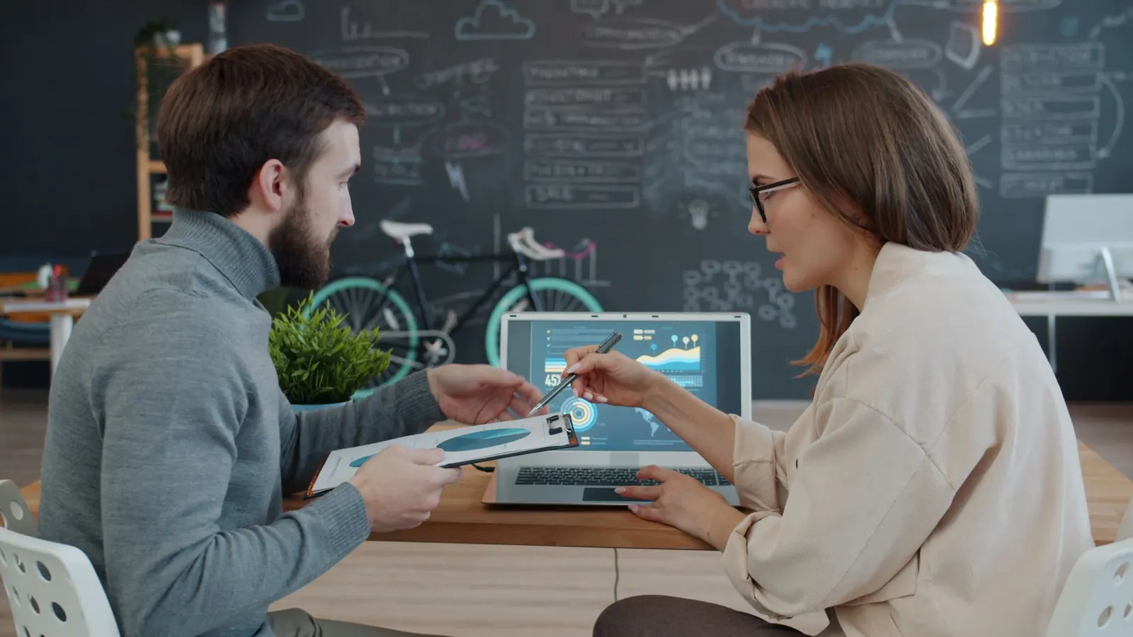 Two professionals discussing data analytics on laptop in creative office. Digital marketing salary: the parts worth your attention