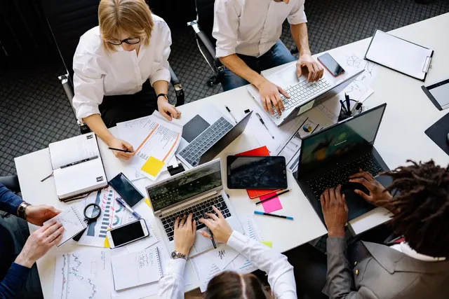 Vibrant office teamwork scene with laptops, documents, and diverse professionals in a meeting. The practical 2027 guide to market research careers